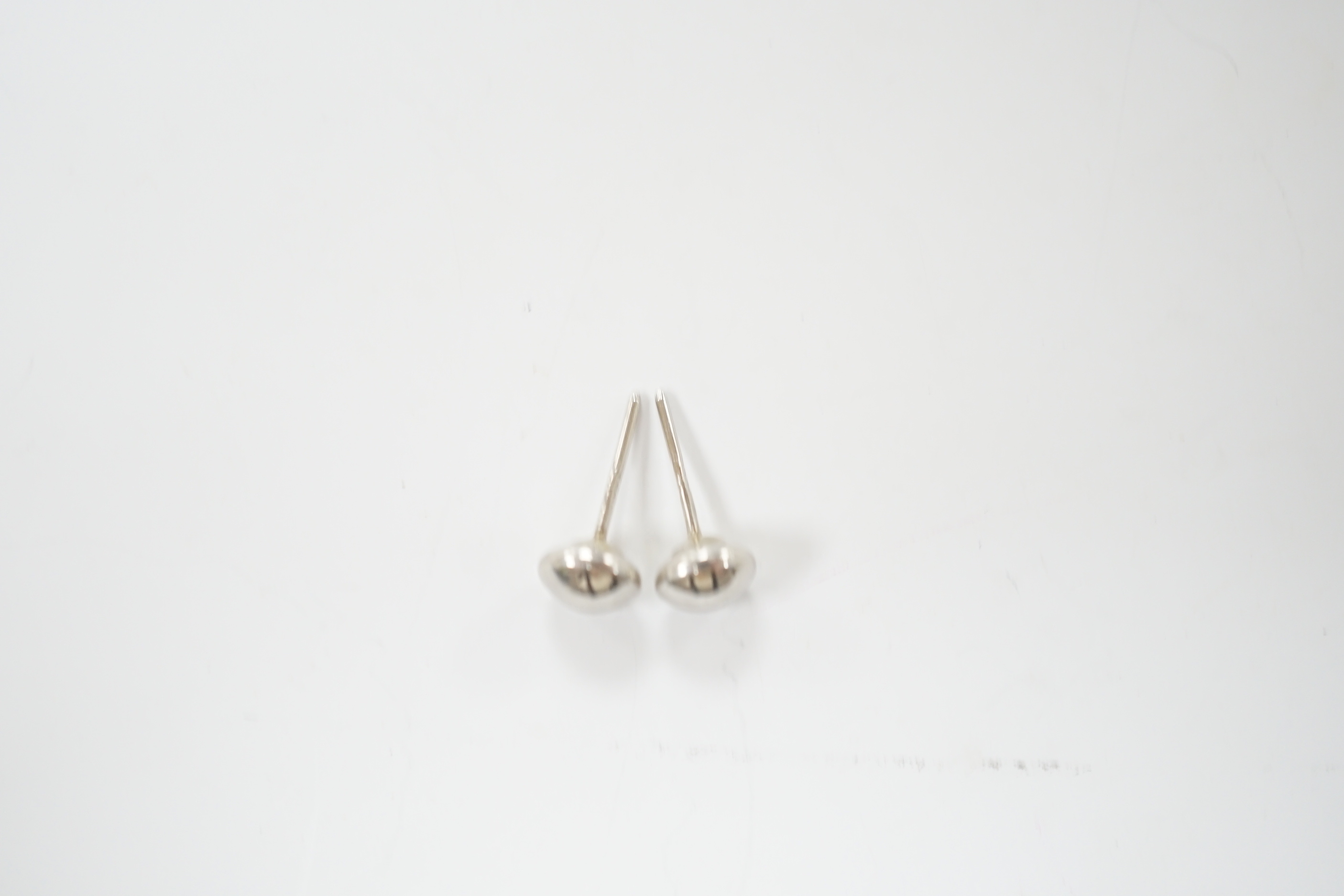 A modern pair of button shaped platinum ear studs, one butterfly missing, 1.1 grams.